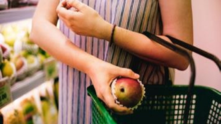 woman putting fruit into her green basket