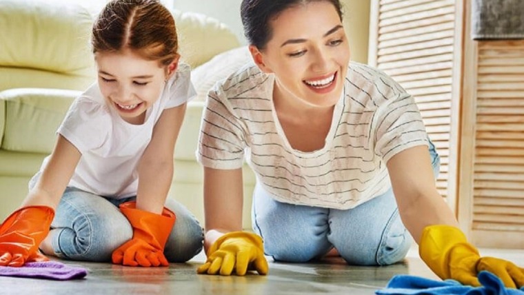 mother and daughter laughing whilst cleaning the floor
