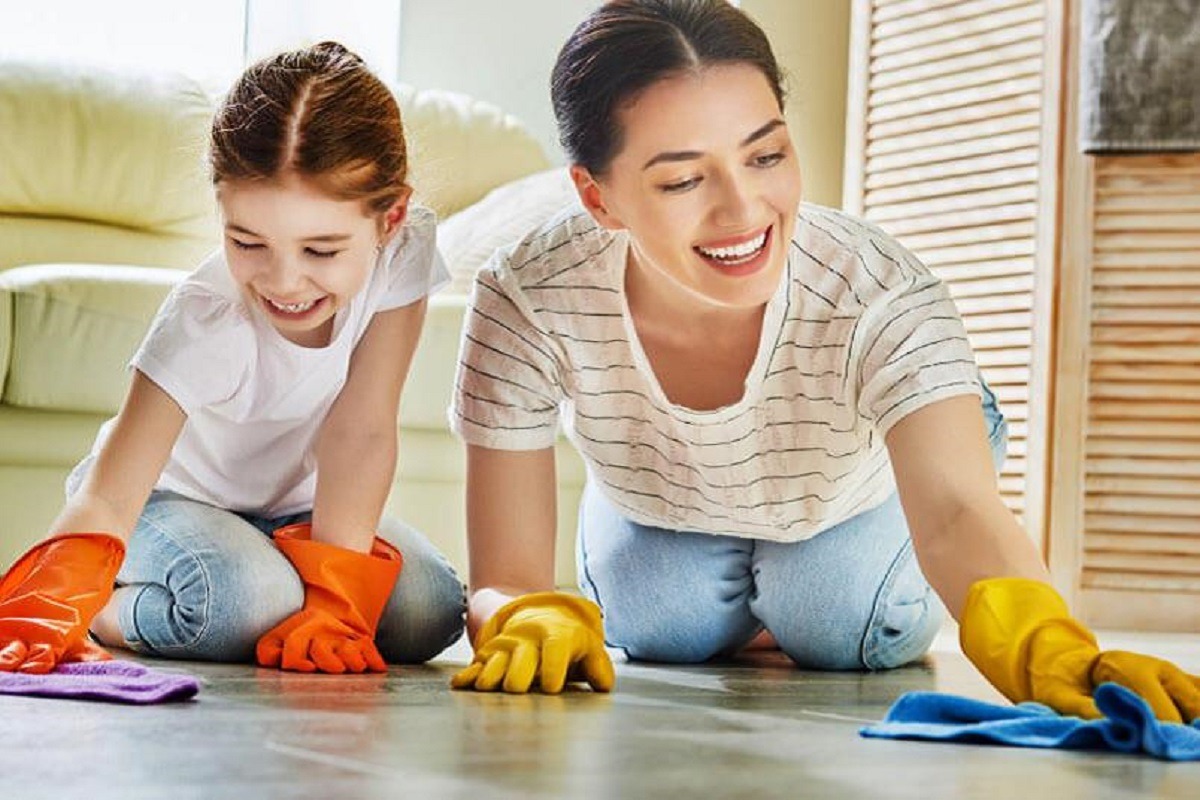 mother and daughter laughing whilst cleaning the floor