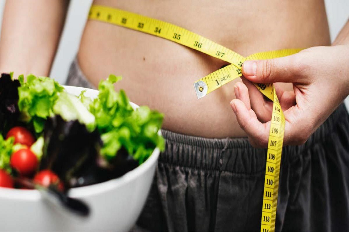measuring waist with bowl of salad