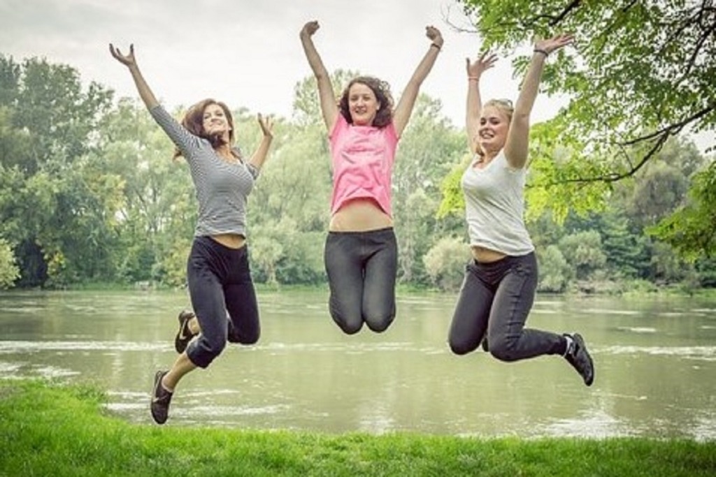 3 women jumping outside near lake