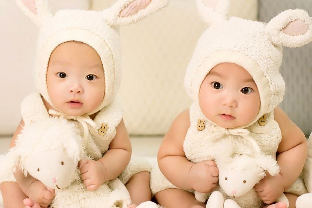 2 asian babies dressed in light onsies with rabbit ears