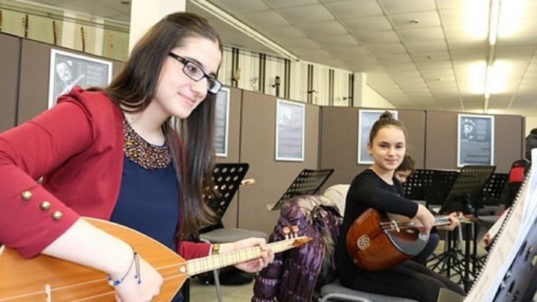 girls sitting playing stringed instruments