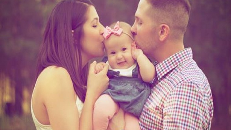 father and mother kissing baby daughter