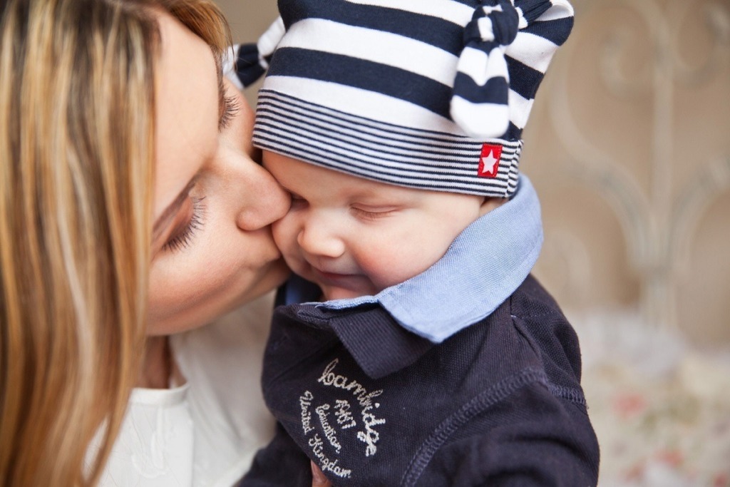 mother kissing baby in stripped cap