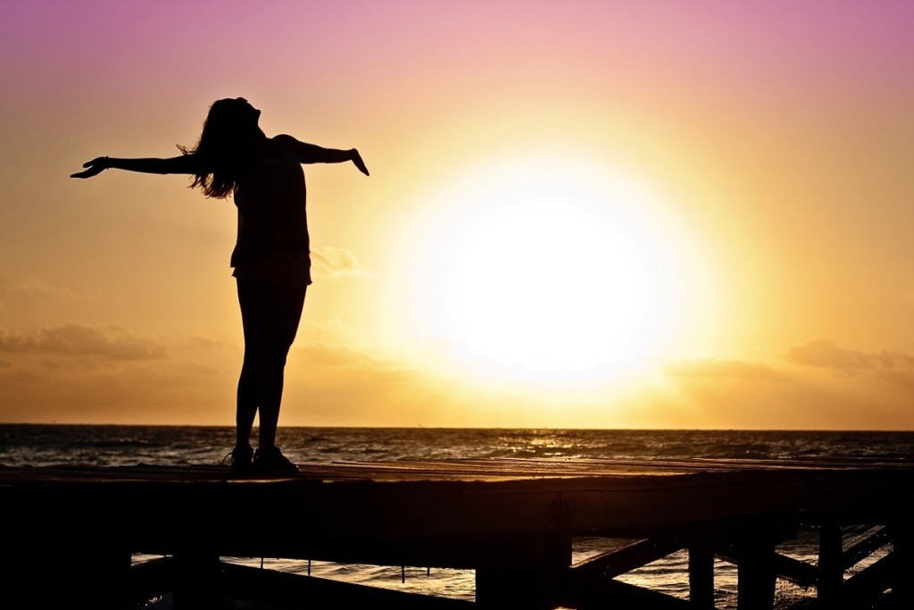 woman facing the ocean enjoying the sunset