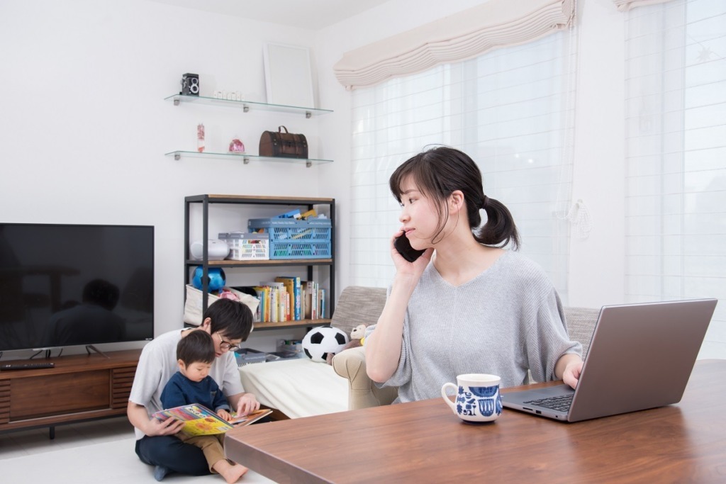 Asian mother on mobile in front of laptop