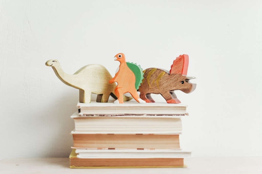 wooden dinos on stacked books