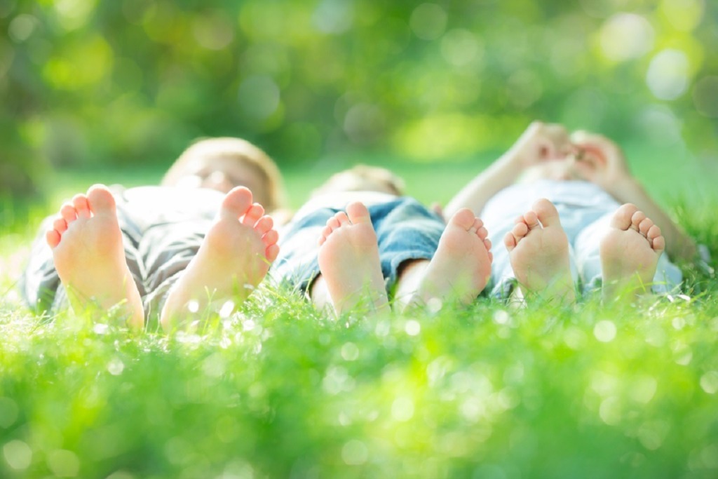 image of the soles of childrens feet laying on grass