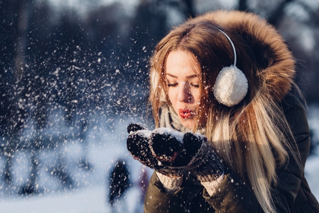 young woman blowing snow off gloves