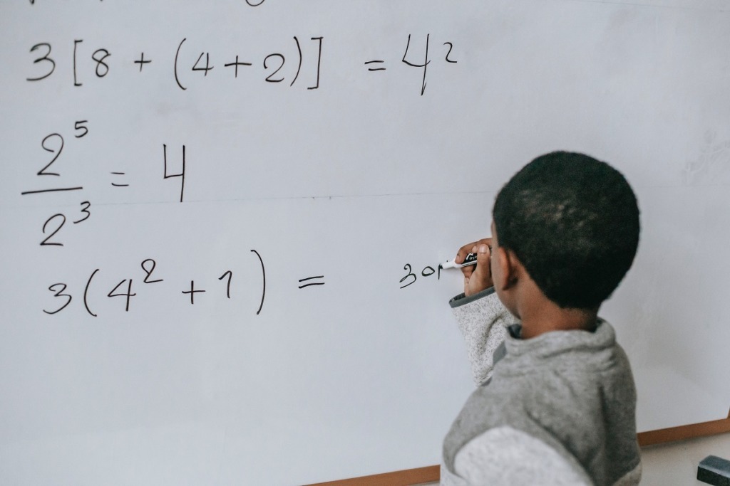 boy writing formula on white board