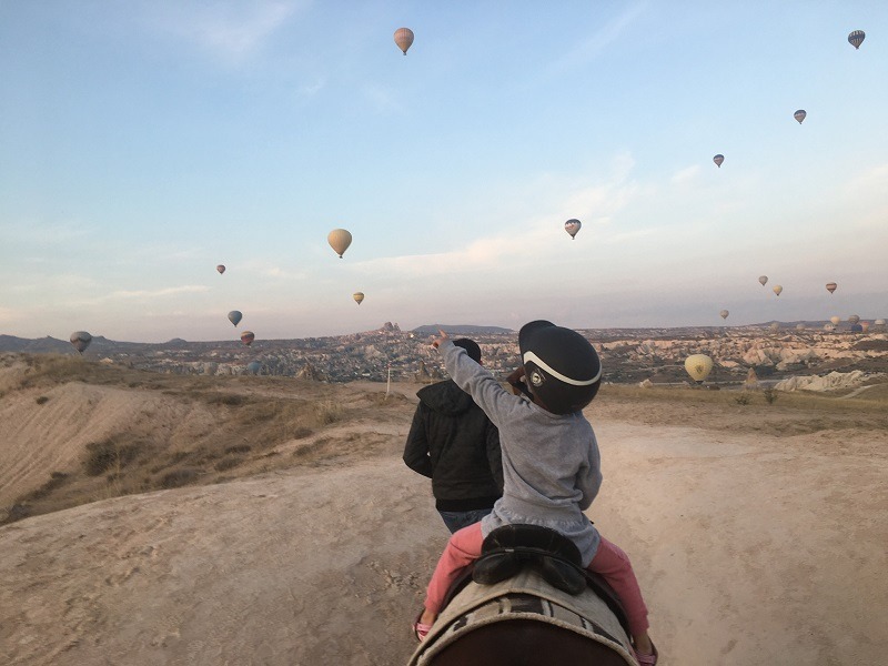 boy on horse being led, looking at hot air balloons