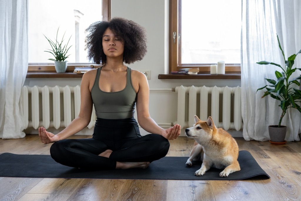 woman meditating on floor beside dog