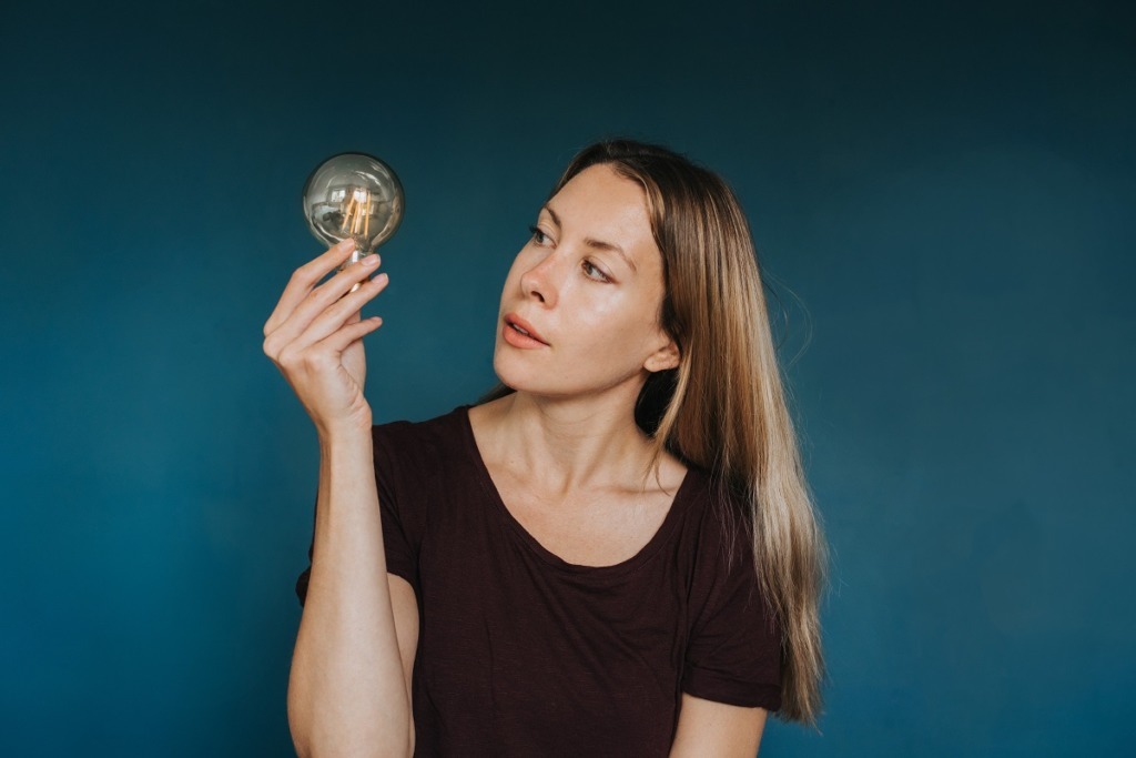 woman holding light globe blue background
