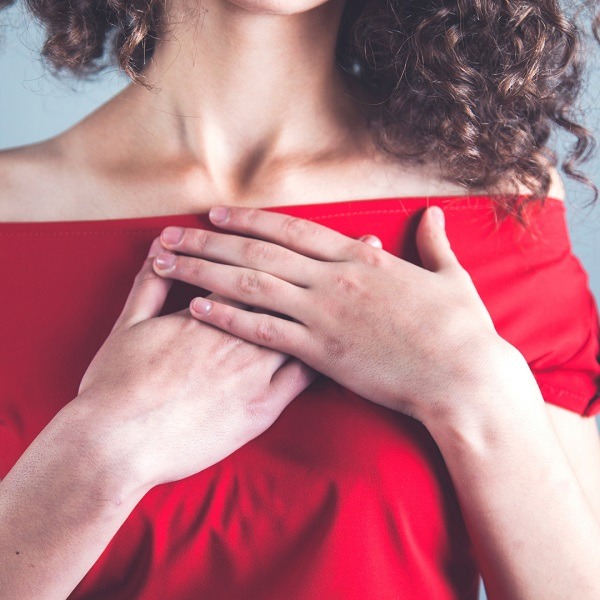 woman in red top with hand on heart